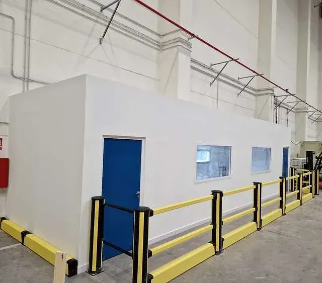 Un almacén con una puerta azul y una barrera amarilla.