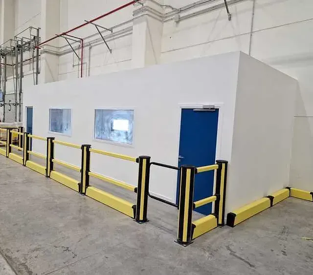 Un edificio con una valla amarilla a su alrededor y una puerta azul.