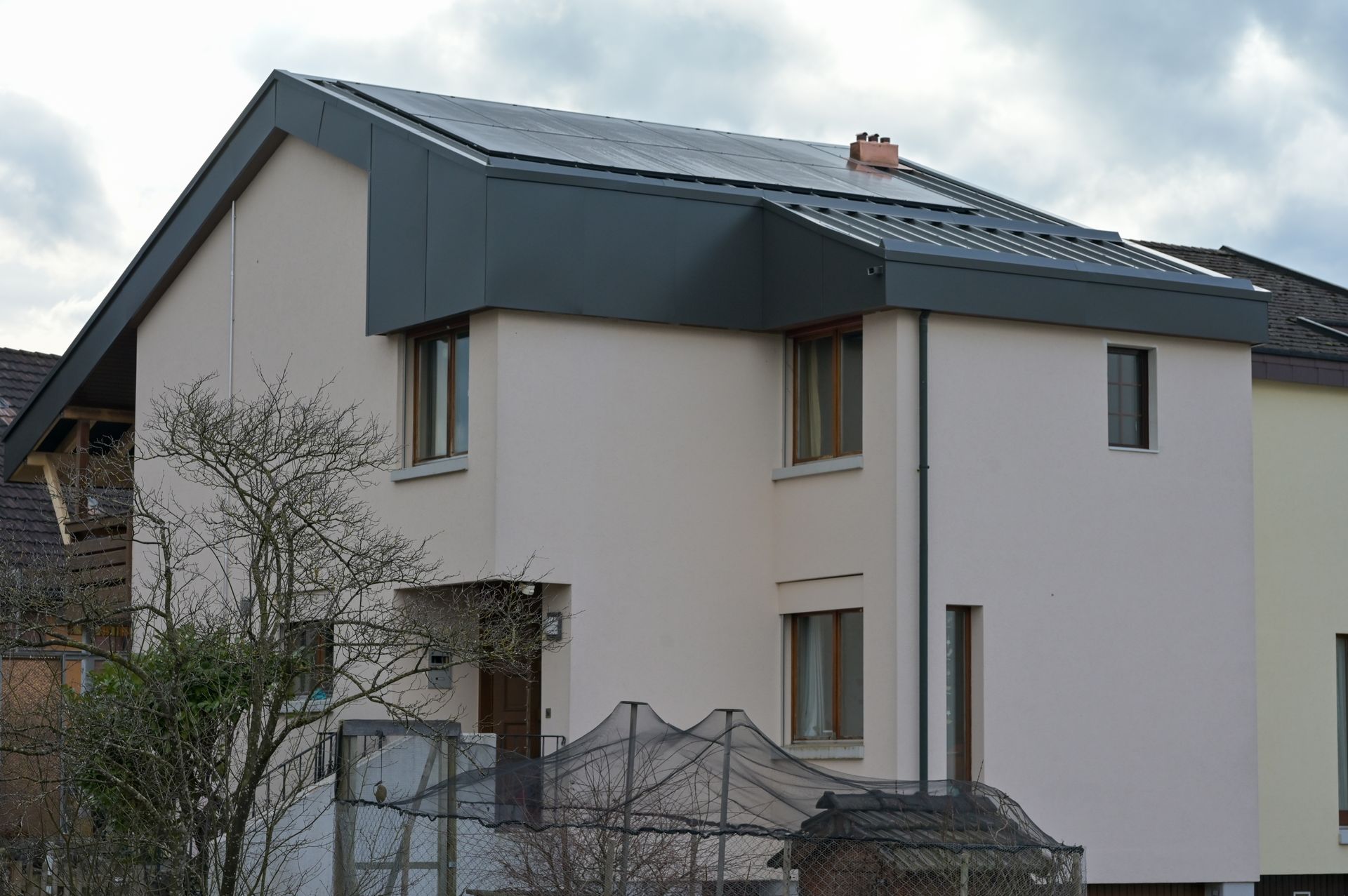 Solarpaneele auf einem Ziegeldach; darunter zwei Fenster.