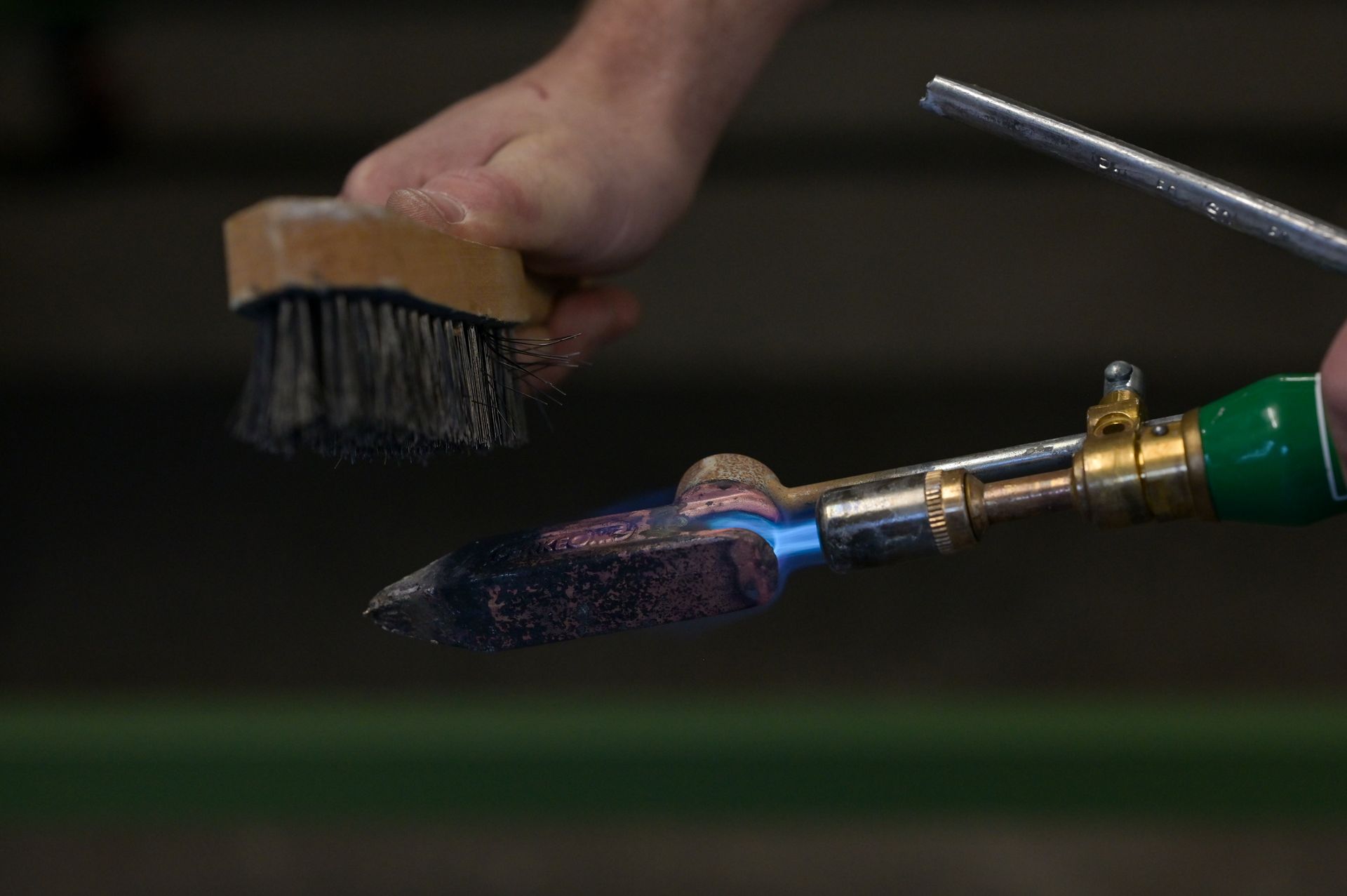 Eine Person formt mit einer Metallwalze ein Blech aus grauem Metall.