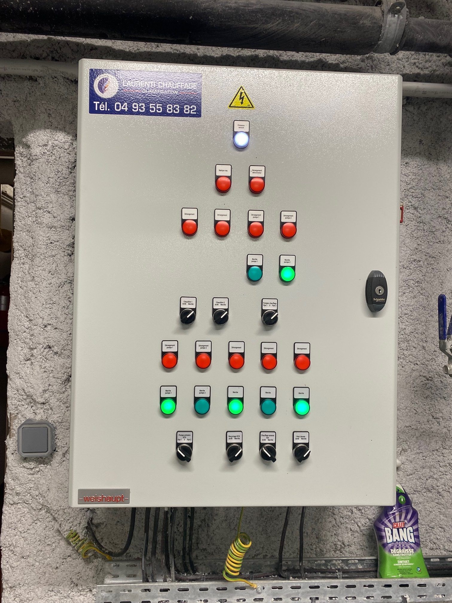 Panneau de commande avec voyants lumineux rouges et verts, fixé au mur.