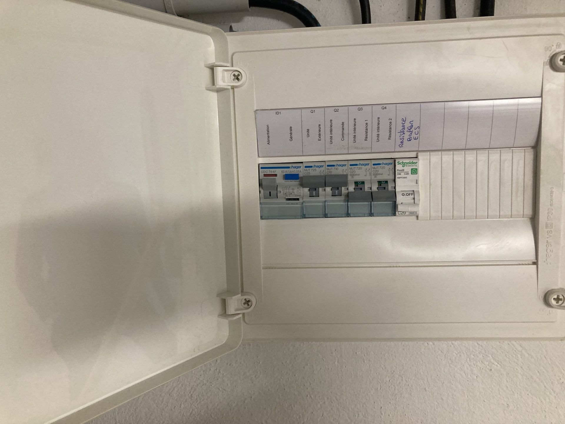 Tableau électrique ouvert avec disjoncteurs. Couvercle blanc, à l'intérieur du mur.