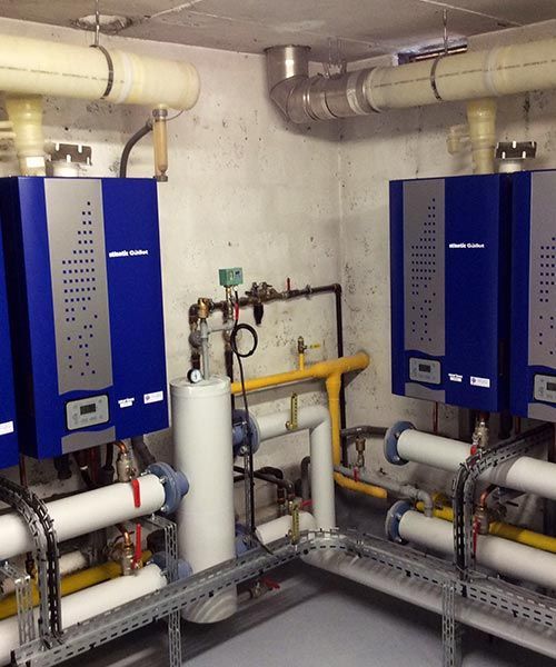 Chaudières bleues avec tuyaux blancs dans une buanderie.