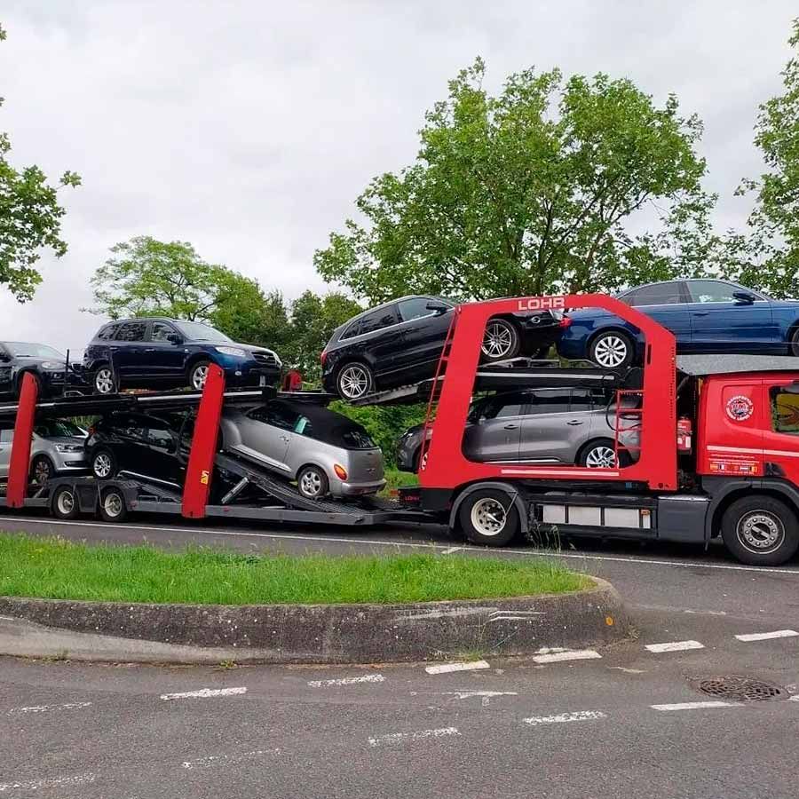 Una grúa roja transporta un montón de coches