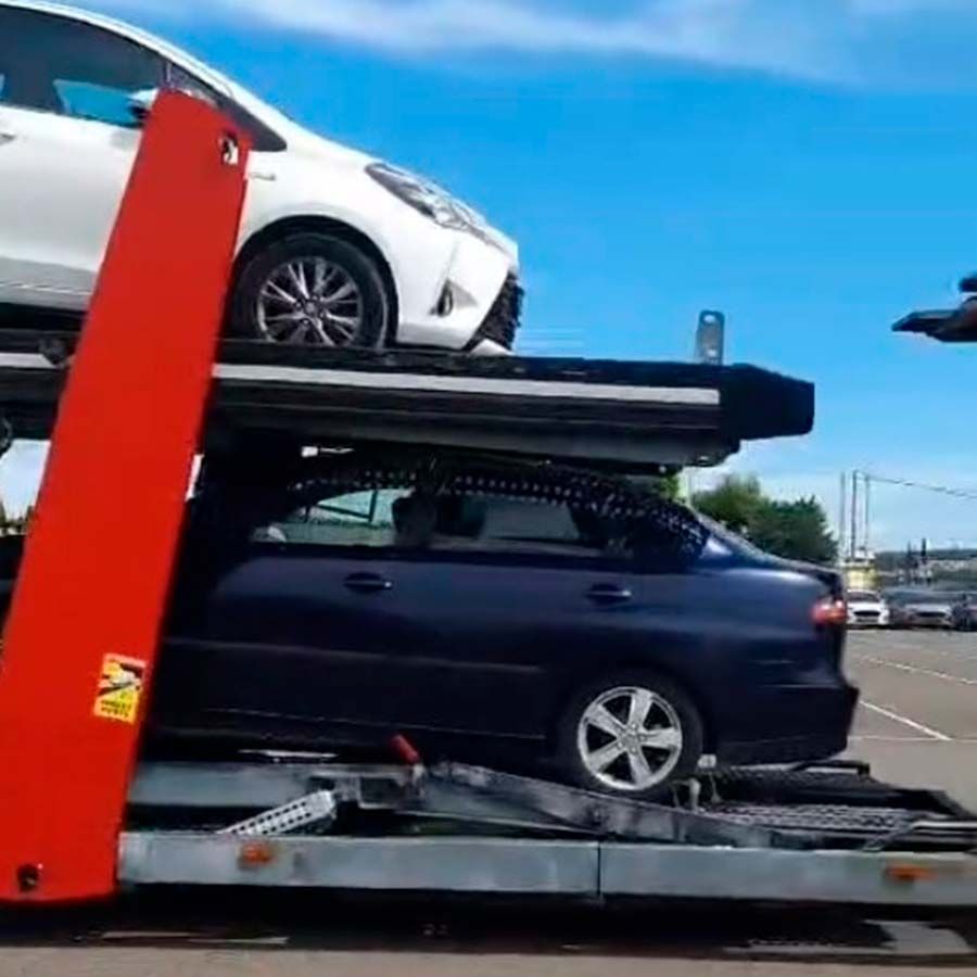 Un automóvil blanco está sentado encima de un automóvil azul en una grúa.