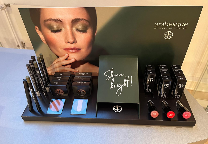 Ein Verkaufsdisplay für Arabesque-Kosmetik mit Lidschatten, Kajalstiften und Lippenstiften in einem schwarzen Ambiente.