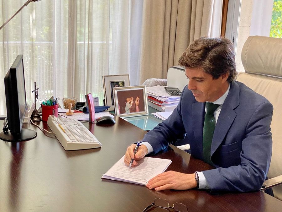 Hombre de traje escribiendo en un escritorio. Oficina.