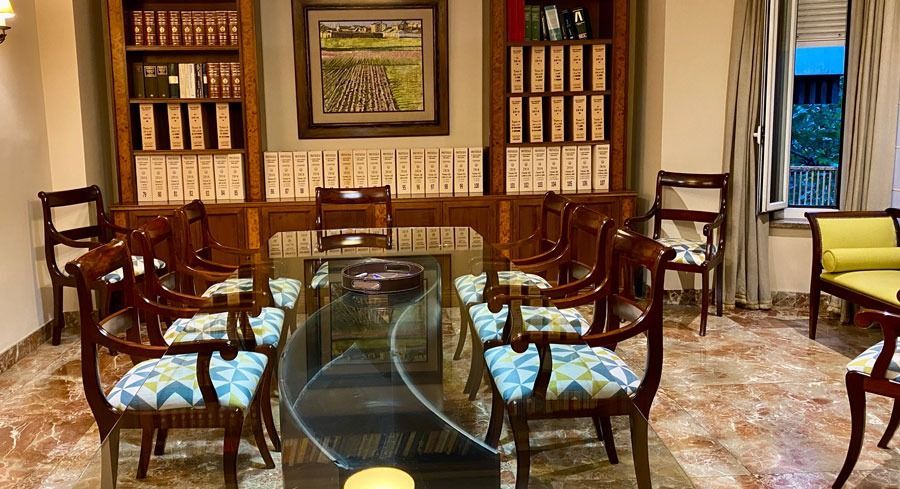 Una sala de reuniones formal con muebles de madera, estanterías y una mesa larga con tapa de cristal.