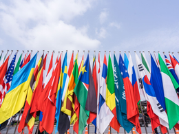 Deux personnes en tenue professionnelle travaillent ensemble, examinant et signant des documents juridiques à un bureau avec une balance de la justice posée dessus.