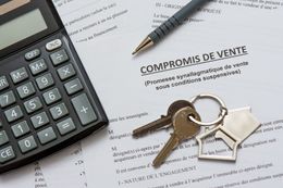 Une calculatrice, un stylo et un porte-clés en forme de maison avec des clés reposent sur un document intitulé compromis de vente.