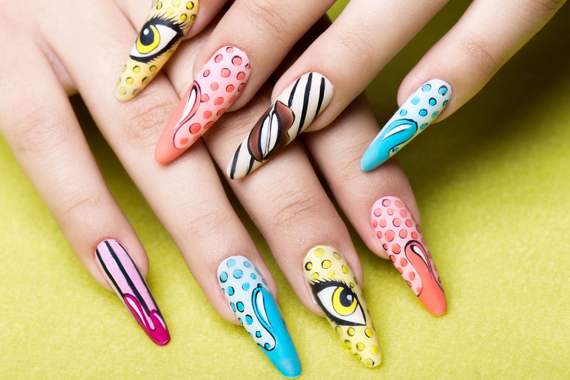 Ongles longs et colorés ornés de motifs animaliers : yeux, taches, rayures et couleurs vives.