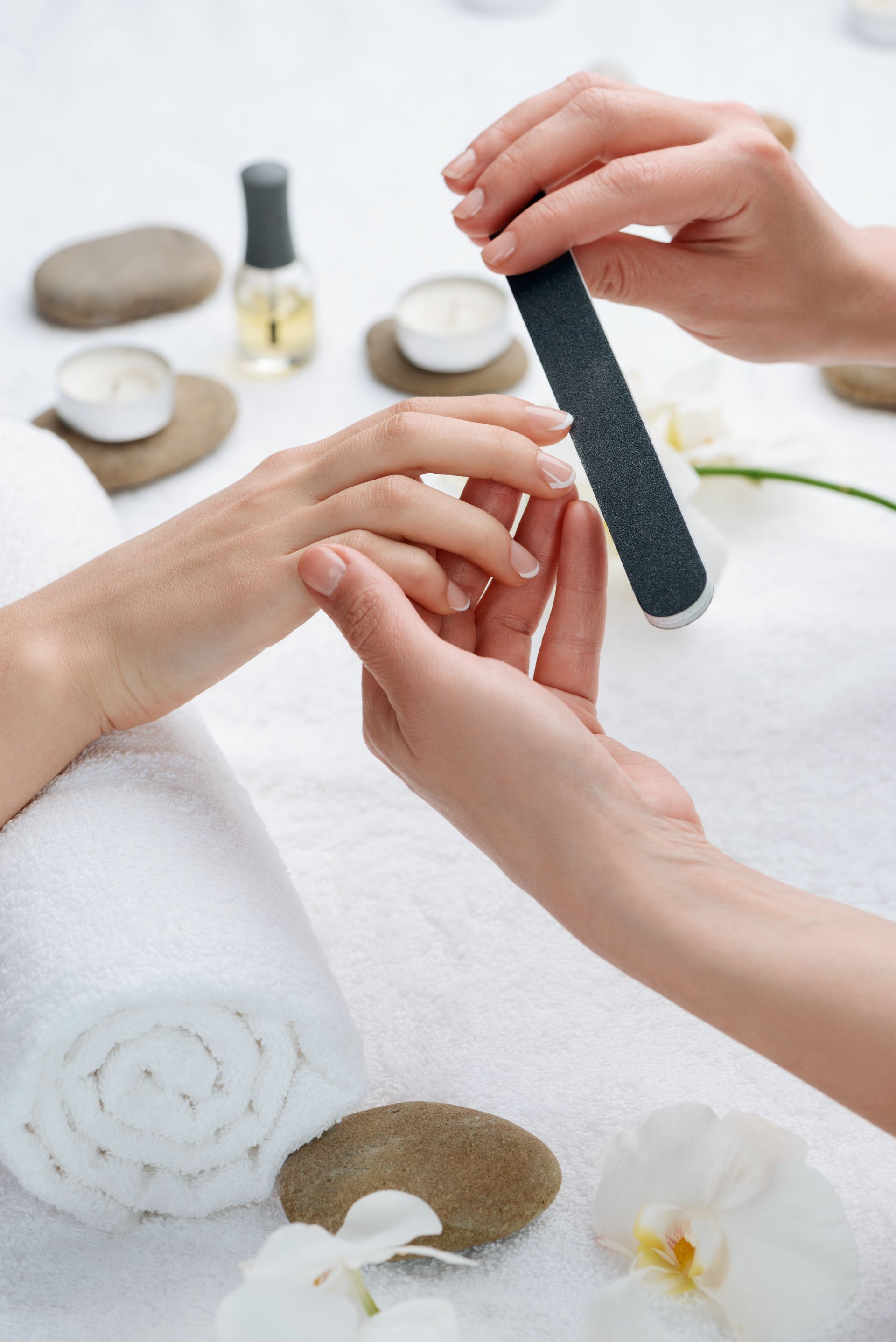 Mains se faisant faire une manucure, ongle limé, ambiance spa.