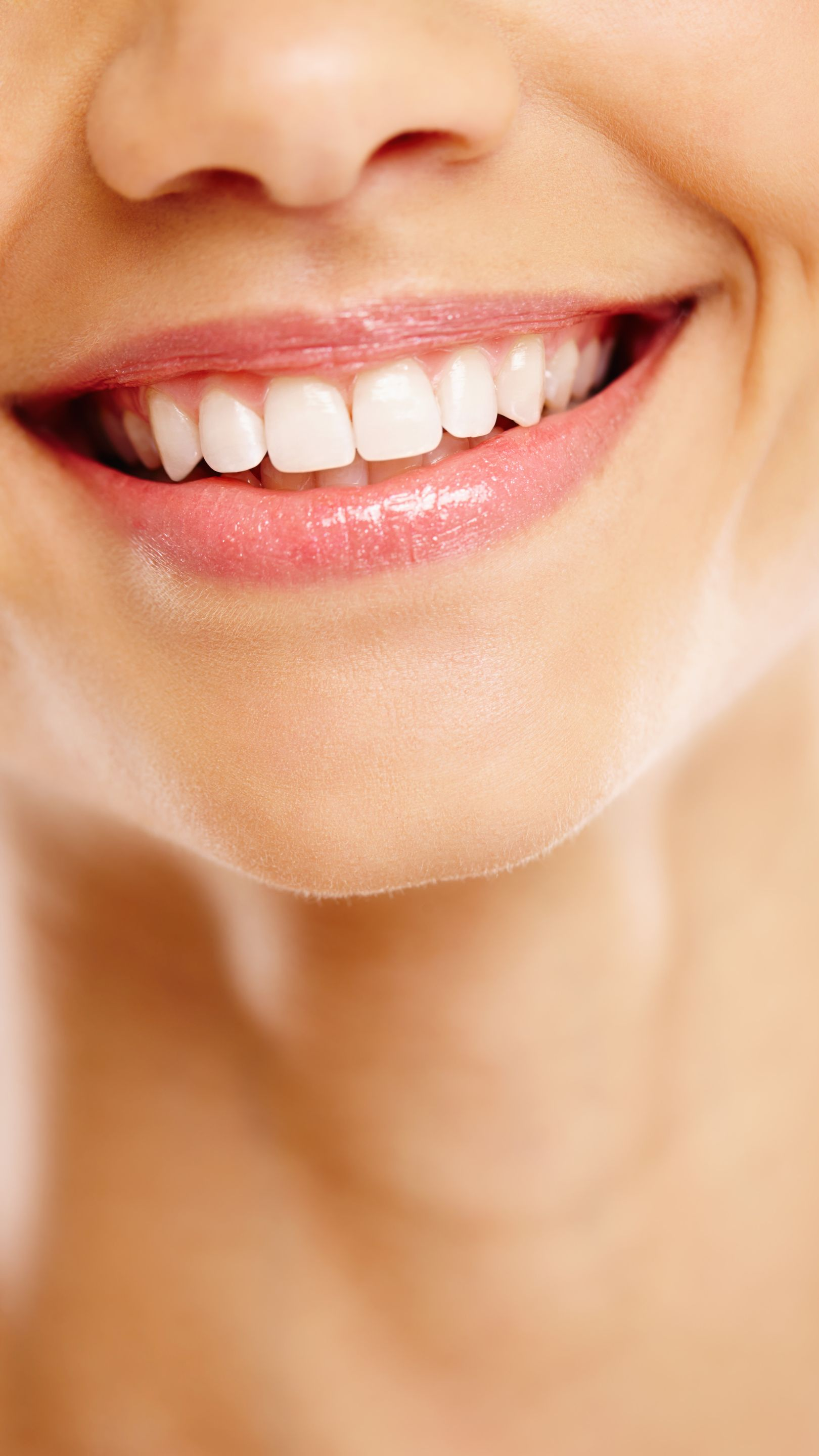 Gros plan sur une bouche souriante aux dents d'un blanc éclatant et aux lèvres roses brillantes.