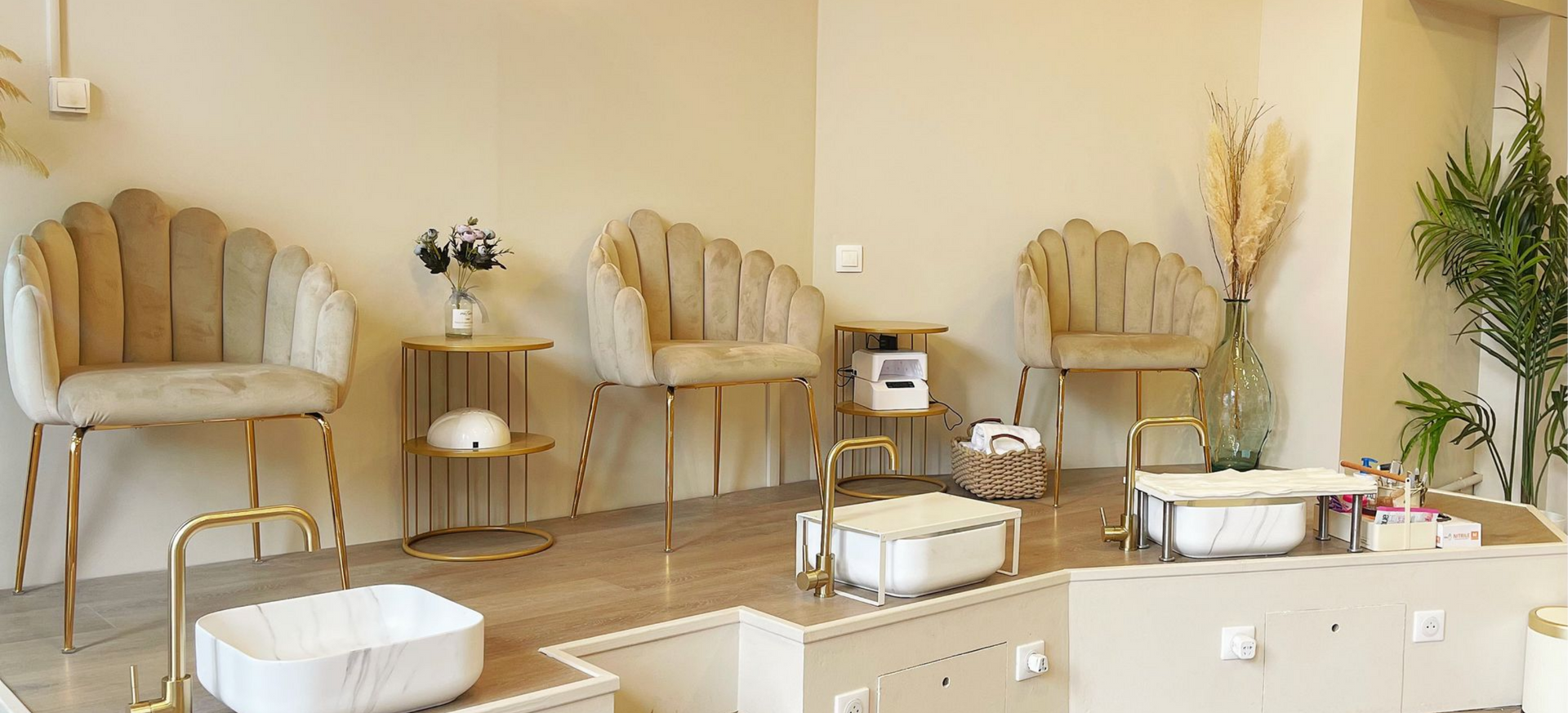 Intérieur d'un salon de manucure avec des fauteuils en forme de coquillage, des touches dorées et des postes de pédicure.