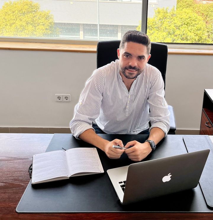 Un hombre está sentado en un escritorio con una computadora portátil Apple.