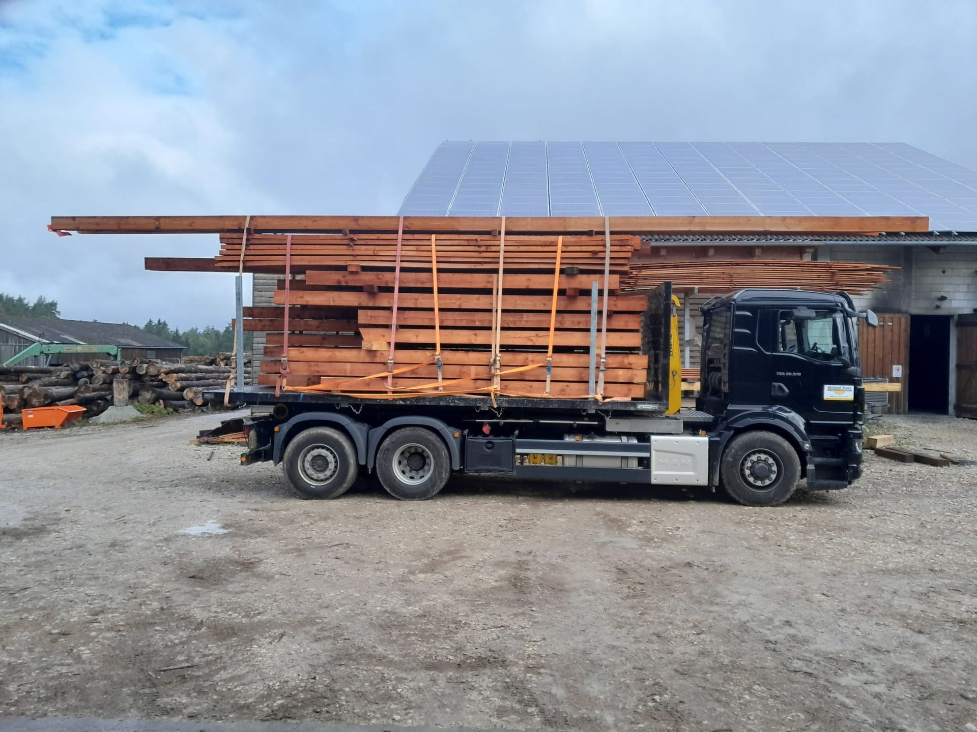 Holztransport mit LKW vor Lagerhalle