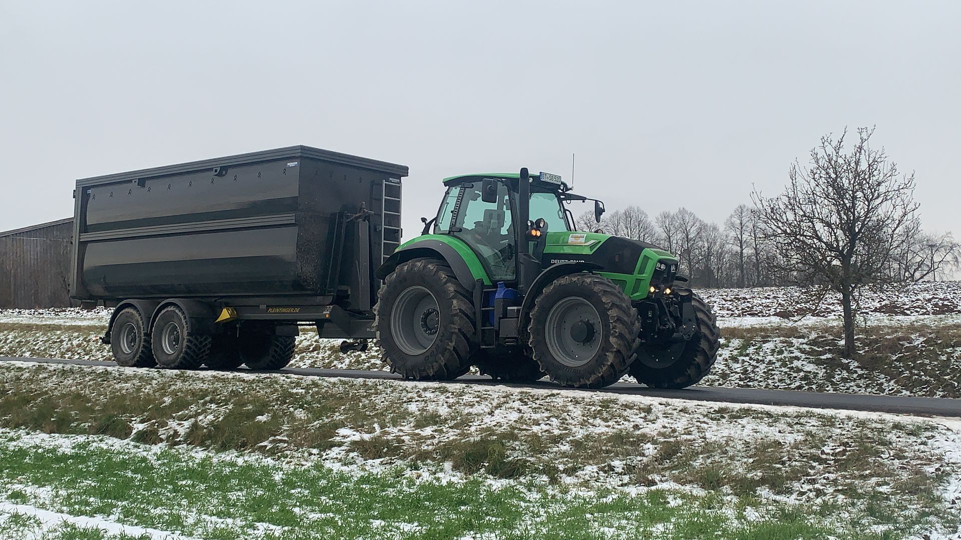 Traktor mit Muldenkipper auf verschneitem Feld