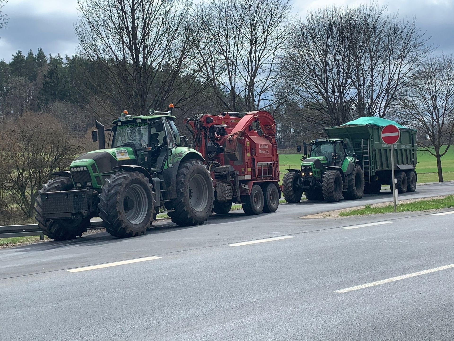 Junger Mann steht vor einem hell erleuchteten Traktor.