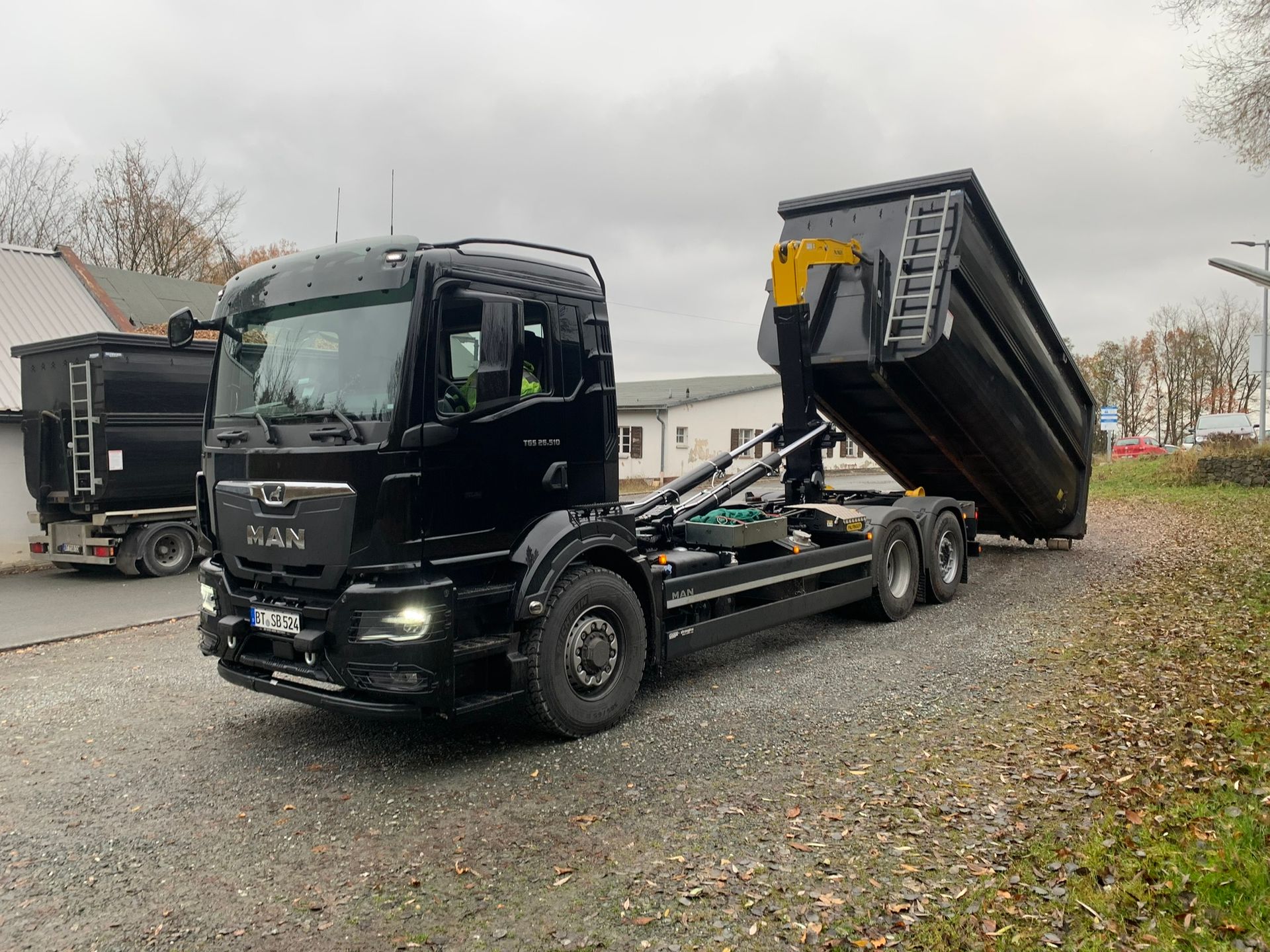 Junger Mann steht vor einem hell erleuchteten Traktor.