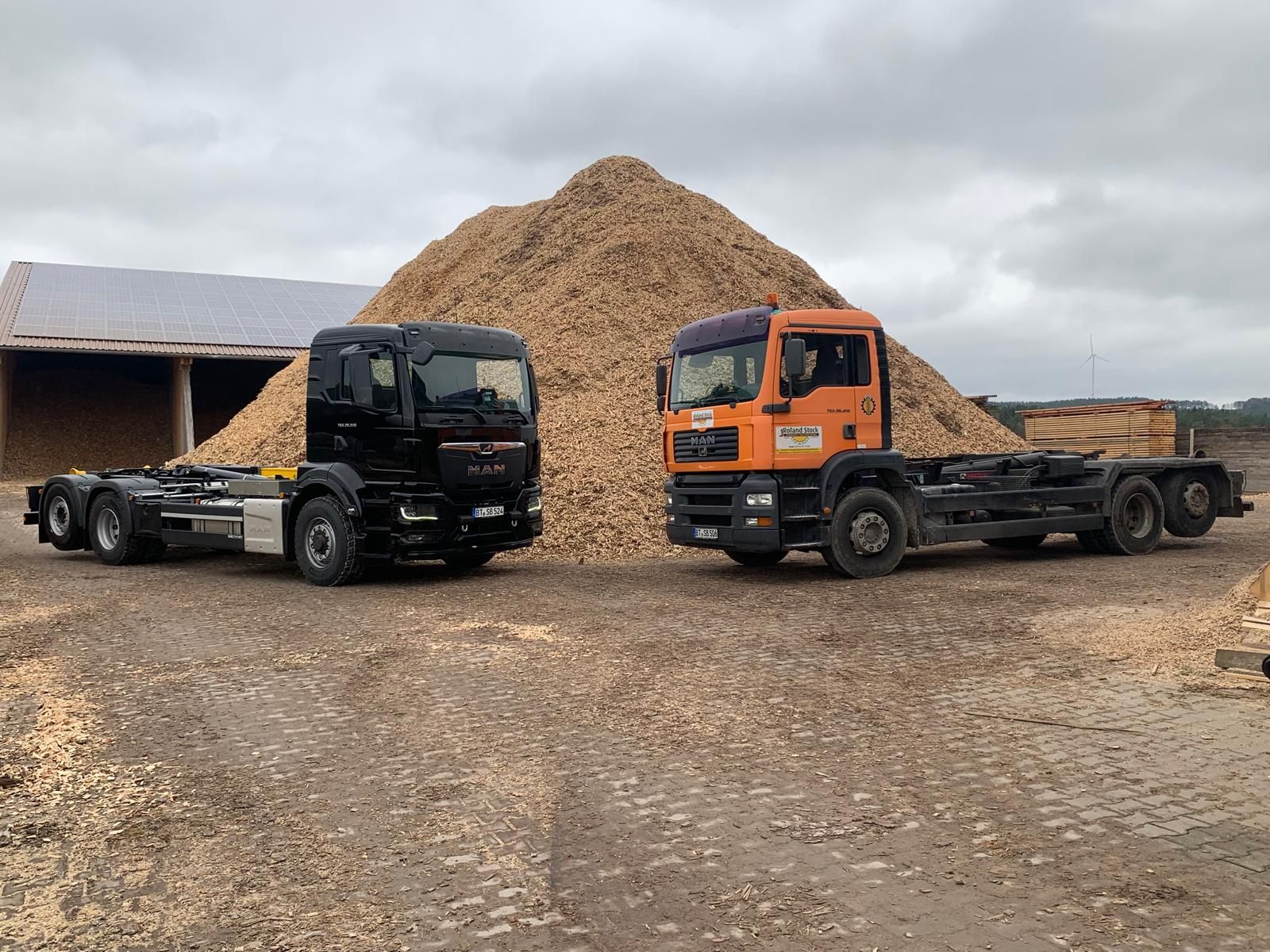 Zwei LKW vor Hackschnitzelhaufen