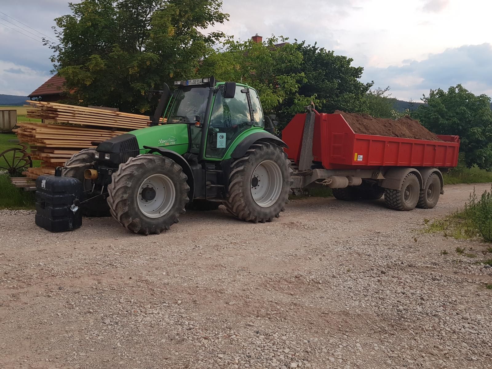 Traktor mit Mulde auf Schotterfläche