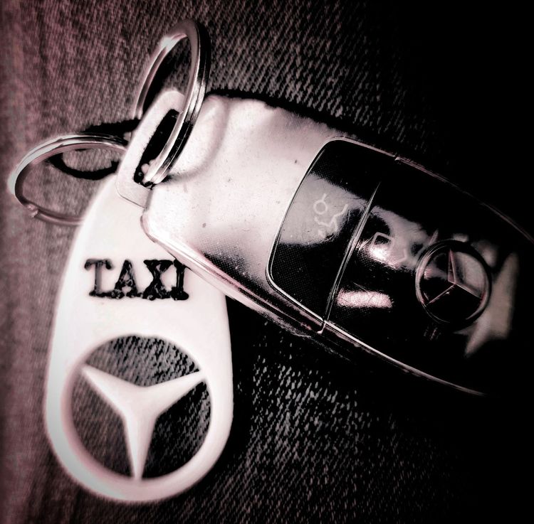 Un llavero que dice taxi junto a la llave de un coche mercedes Benz E220 de Taxi Navalmoral Jesús Picas