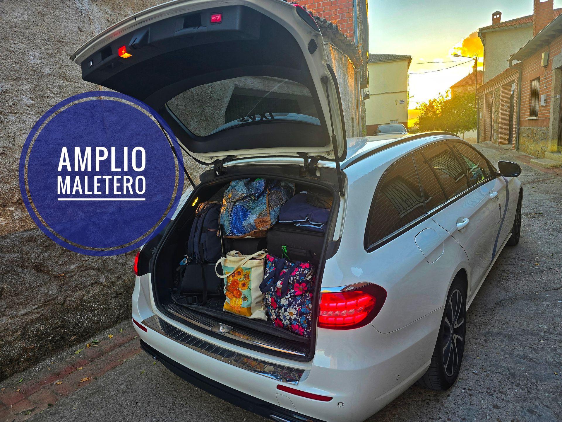 Taxi de Jesús Picas Mercedes E220 State blanco en una calle de Berrocalejo con el portón del maletero abierto mostrando sugrancapacidad lleno de bolsos y maletas..