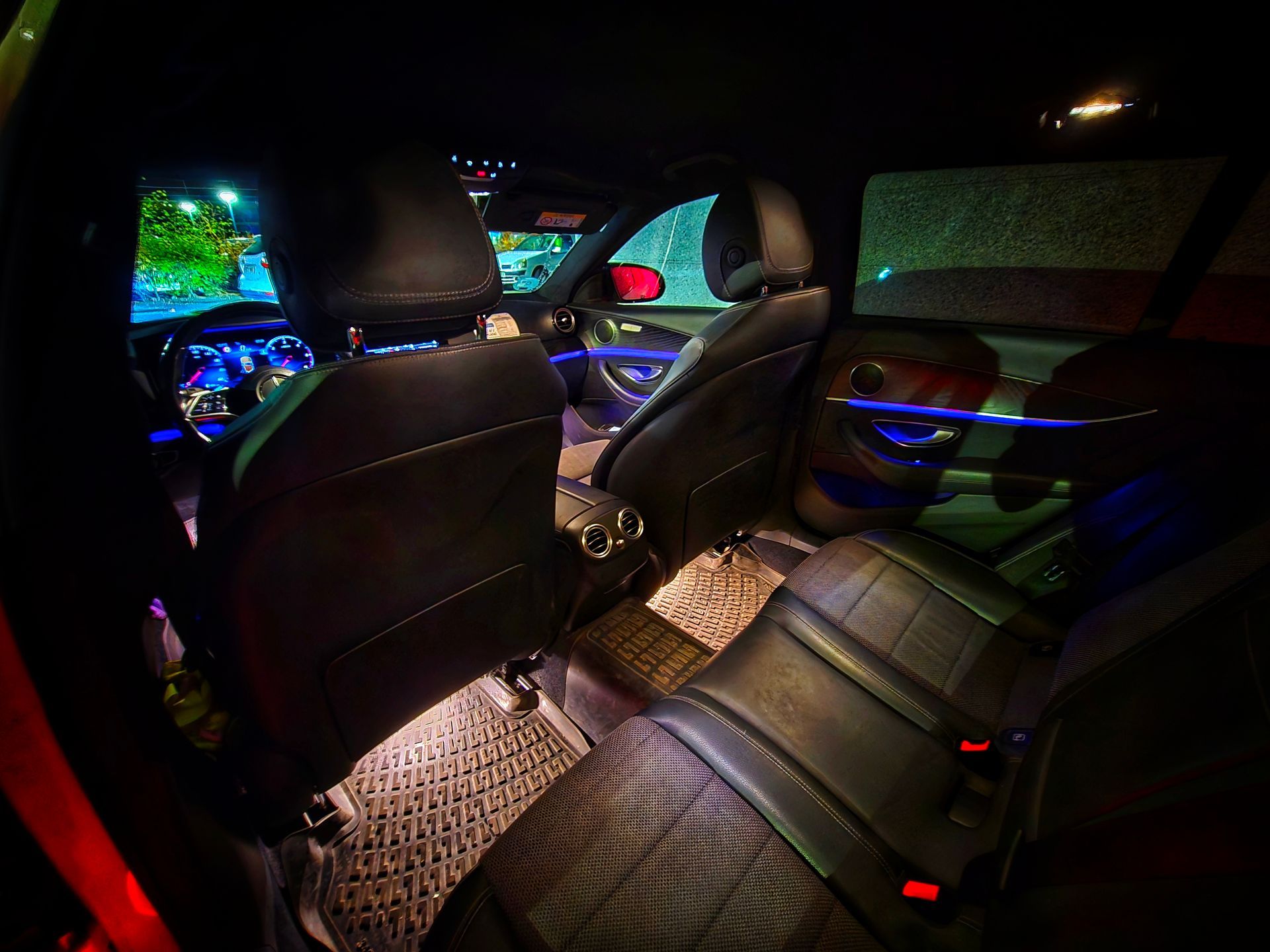 Vista interior de un Taxi Mercedes E220 de Navalmoral con asientos de cuero negro, iluminado por luces azules y blancas.