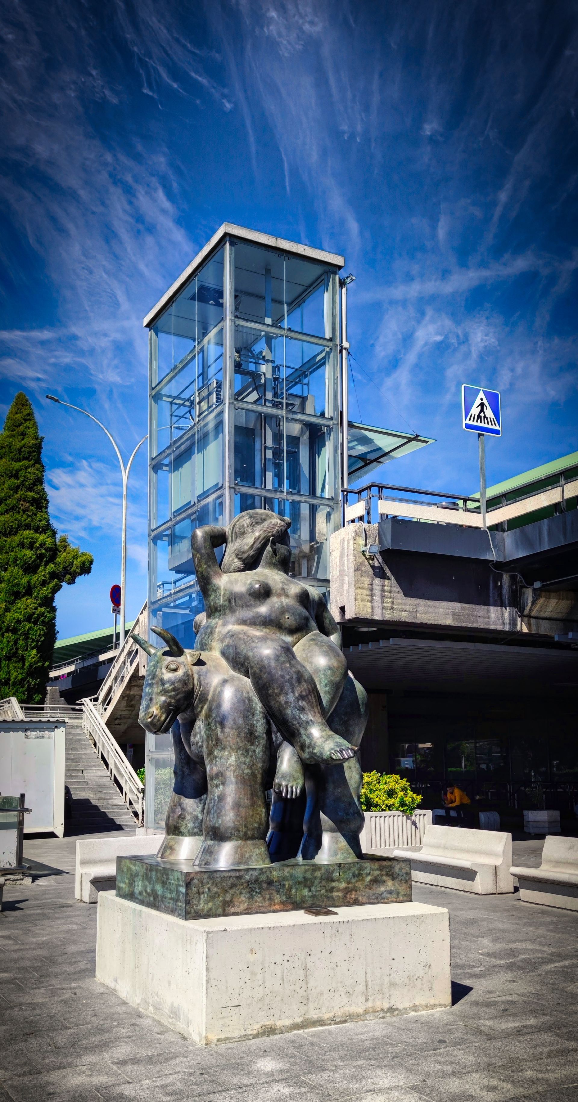 Una escultura de bronce  de Botero que representa una figura sentada sobre un gran animal. En la T1 de Madrid Barajas.