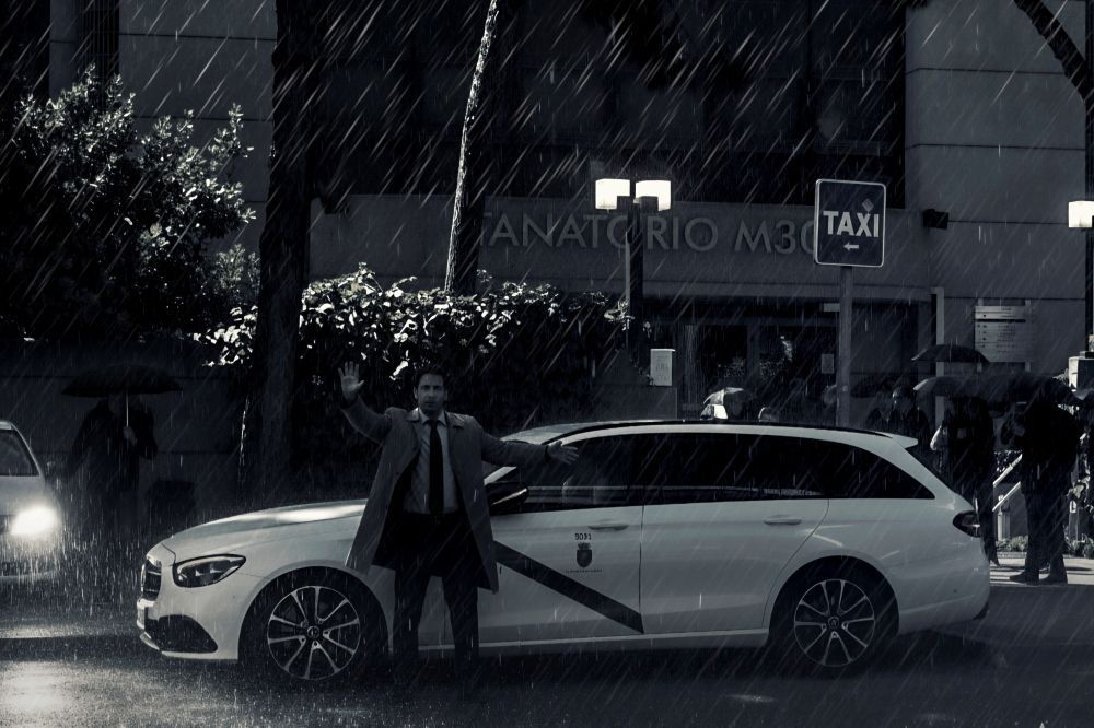 Un hombre bajo la lluvia frente al edificio