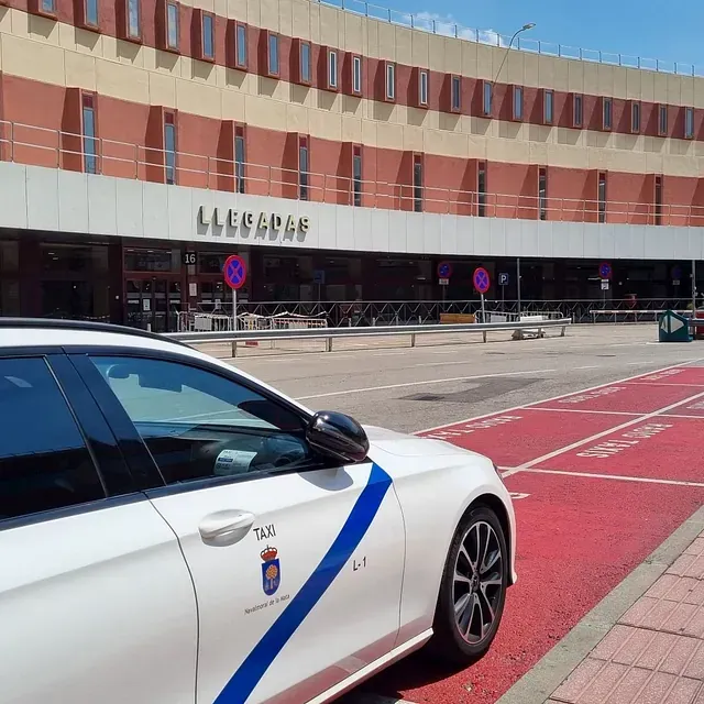 Taxi de Navalmoral Jesús Picas en la T2 Un taxi blanco está estacionado frente a la treminal 2 llegadas del aeropuerto Madrid-Barajas.
