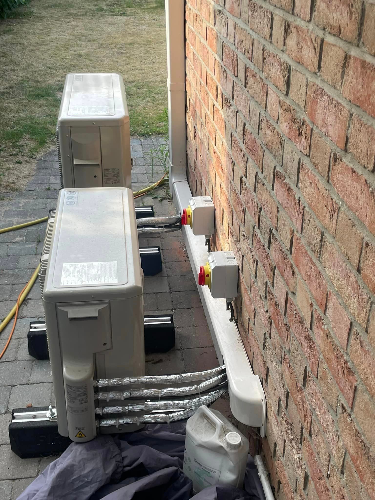 Deux pompes à chaleur vues de profil et branchées à des prises au mur