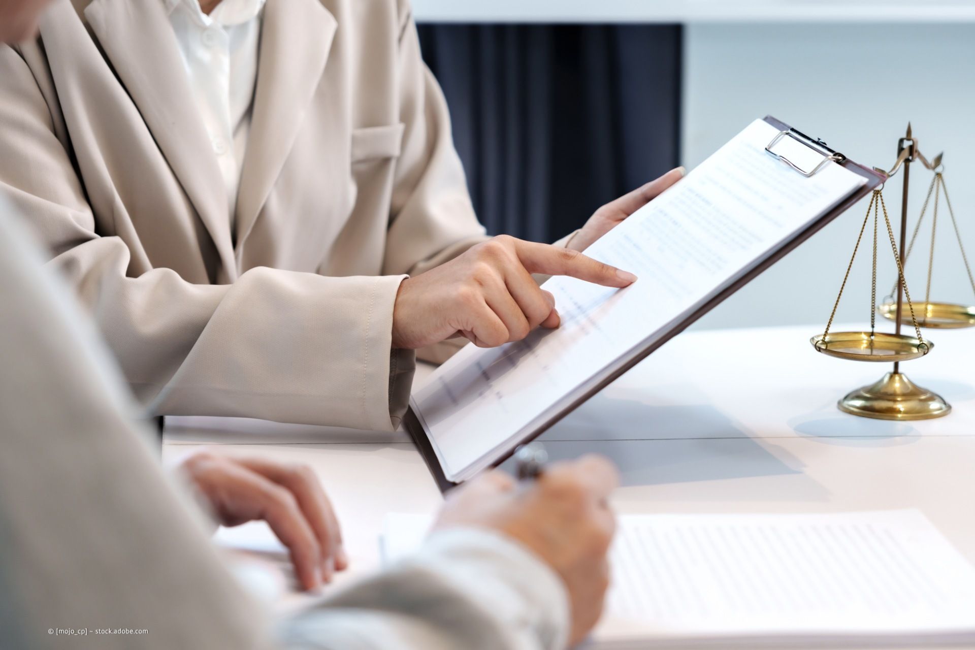 Frau ist in einer Besprechung und weist auf ein Blatt Papier