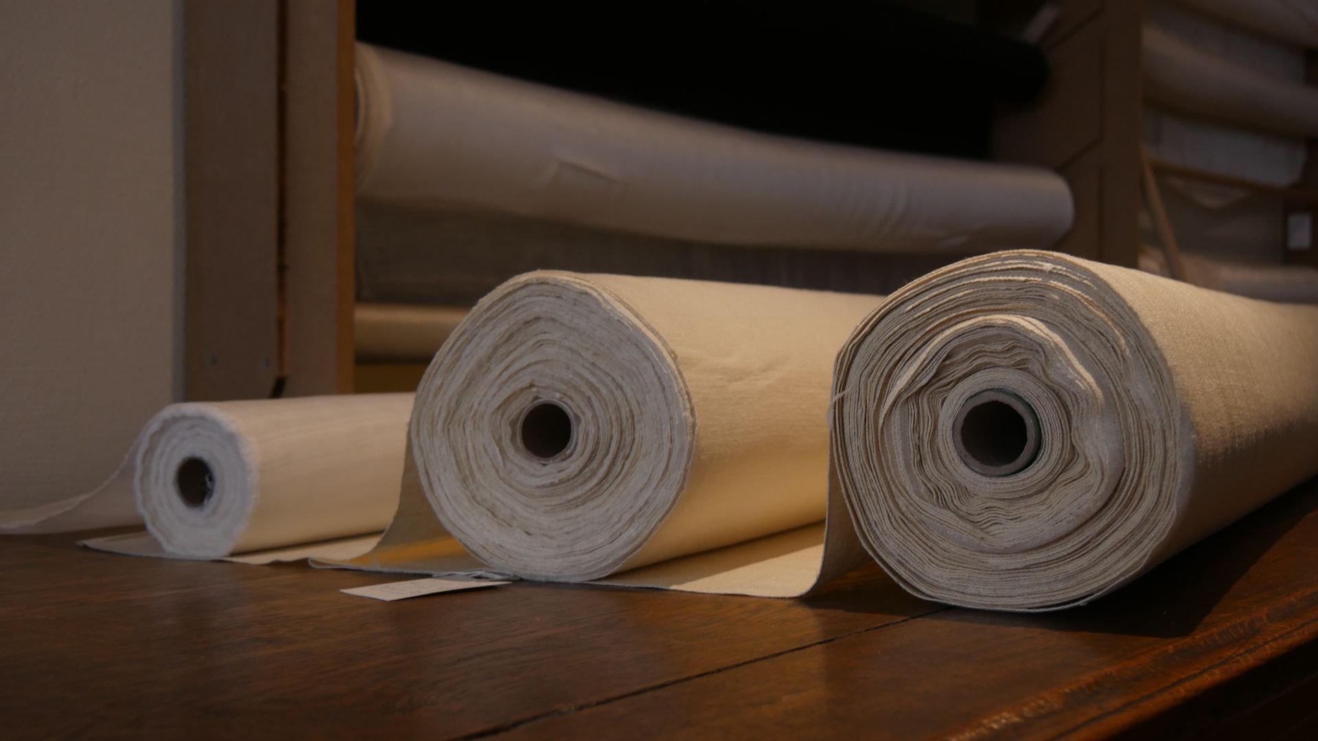 Ciseaux posés sur un tissu fleuri plié, sur une table de découpe en bois.