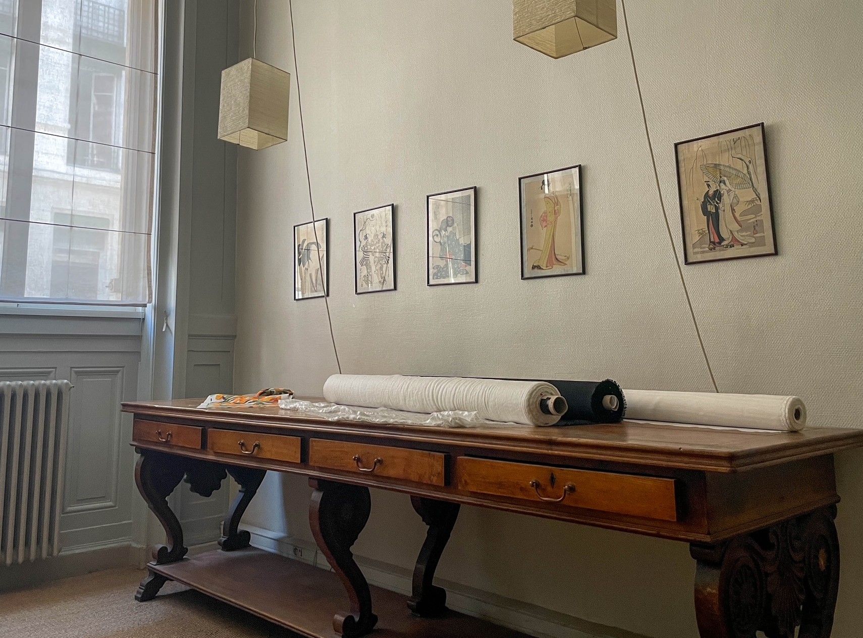 Pièce minimaliste avec un banc en bois, des tableaux encadrés au mur et une grande fenêtre.