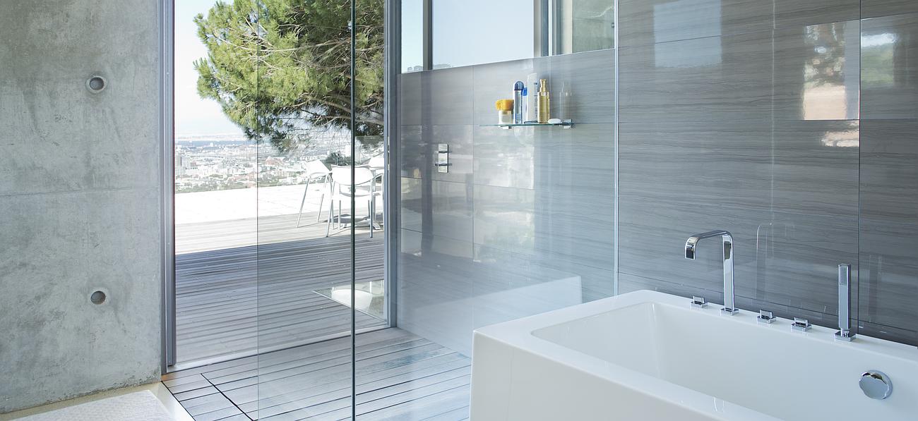 Salle de bains avec baignoire et fenêtre ouverte sur un jardin et une terrasse