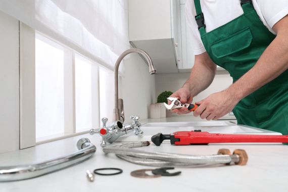 Un fontanero está arreglando un grifo en una cocina.