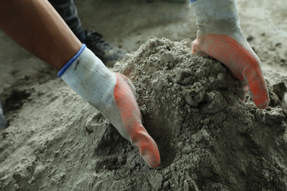 Eine Person mit Handschuhen arbeitet mit Sand.