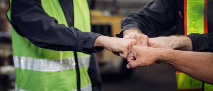 Eine Gruppe von Bauarbeitern legt ihre Hände zusammen.