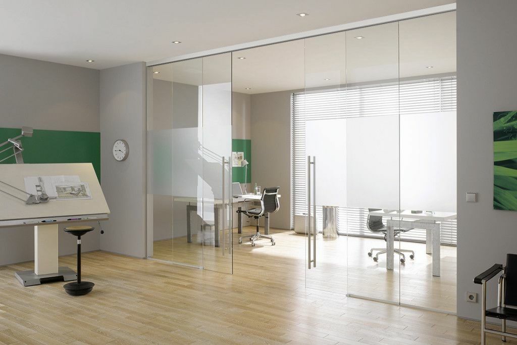 Modernes Büro mit Glaswänden, Zeichenbrett, Schreibtischen und Holzboden.