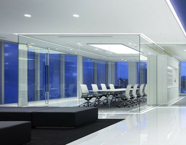 Moderner Bürobesprechungsraum mit Glaswänden, weißem Tisch, Stühlen und Blick auf die dunkelblaue Nacht.