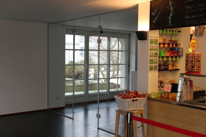 Innenaufnahme: Glastür, Café-Theke mit Snacks, Blick nach draußen durch die Fenster.