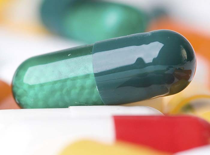 Una cápsula verde está encima de una cápsula blanca.