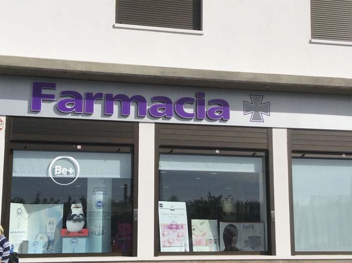 Una farmacia con un cartel morado encima.