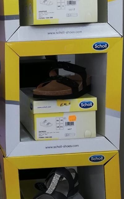 Un par de sandalias se encuentra encima de una caja que dice Scholl