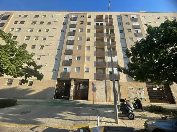 Un gran edificio de apartamentos con scooters estacionados enfrente.