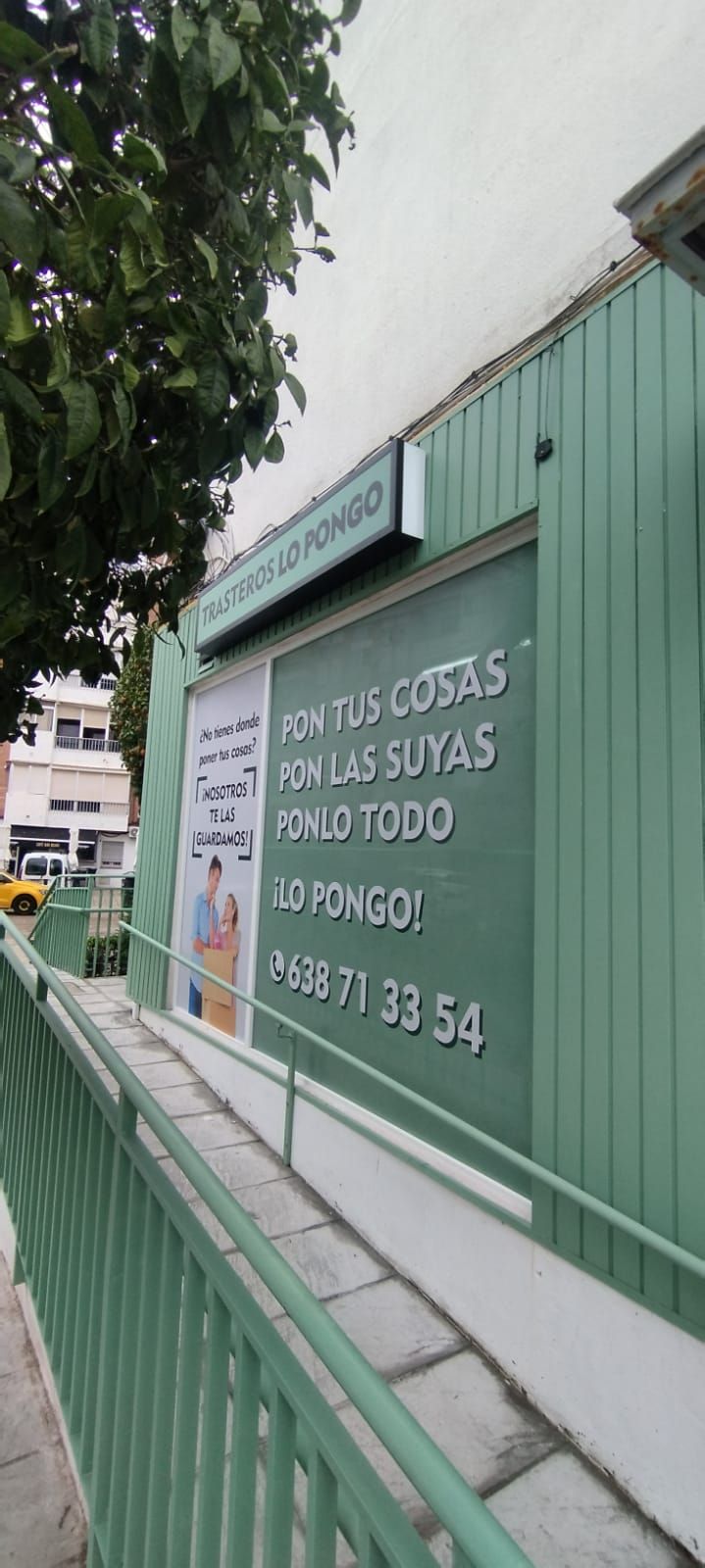 Edificio ecológico con letrero y rampa. El letrero incluye texto y un número de teléfono.