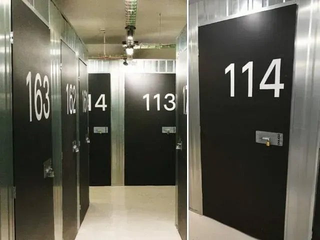 Un pasillo con puertas negras y números blancos en ellas.