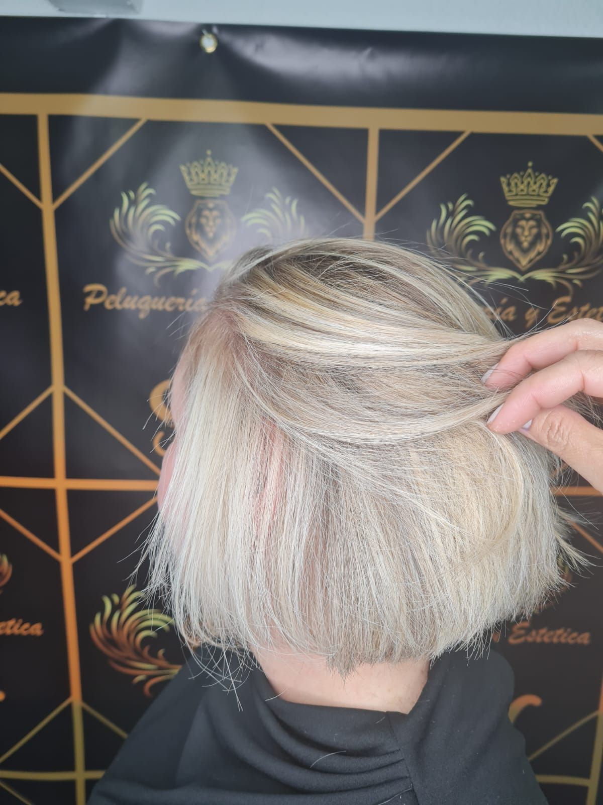 Una mujer con cabello rubio se está cortando el pelo.