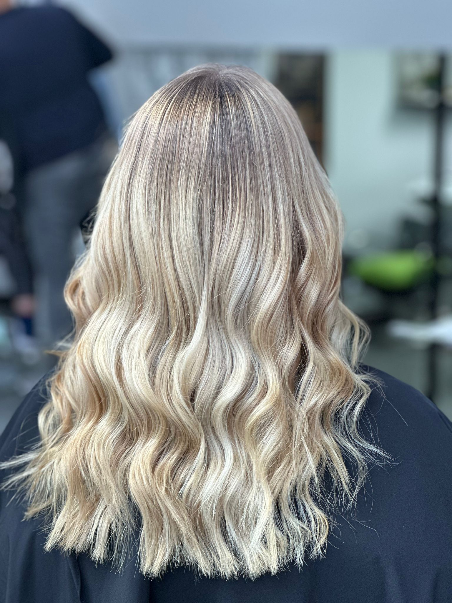 Una mujer con cabello largo y rubio está sentada en una silla en un salón.